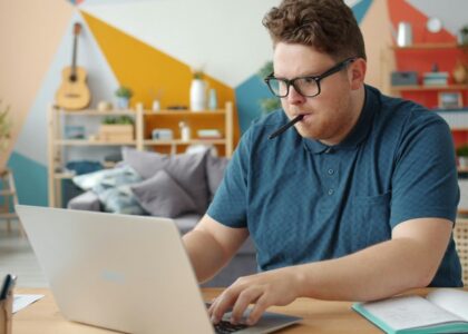 person studying at desk with laptop and notes