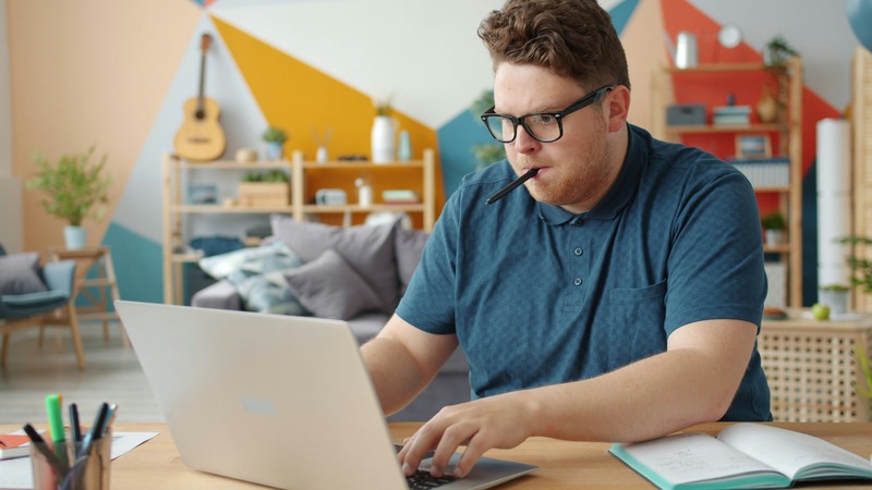 person studying at desk with laptop and notes